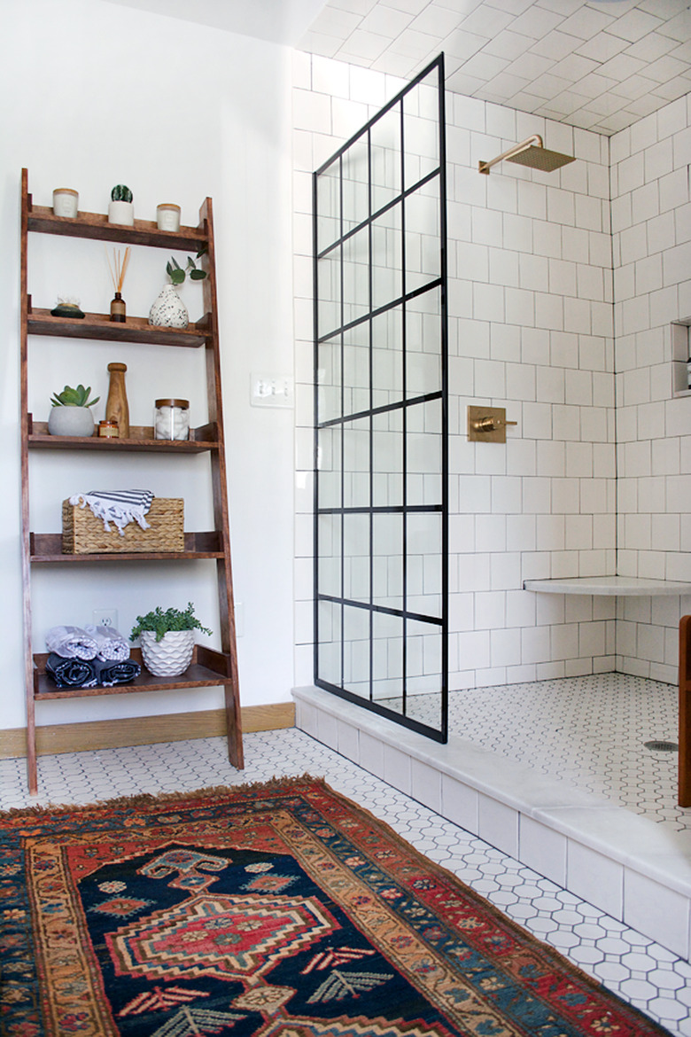 Brass rain showerhead with white tile surround in modern industrial bathroom