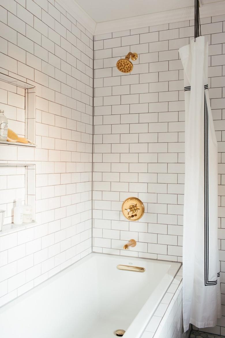 Brass plumbing fixtures with white subway tile shower