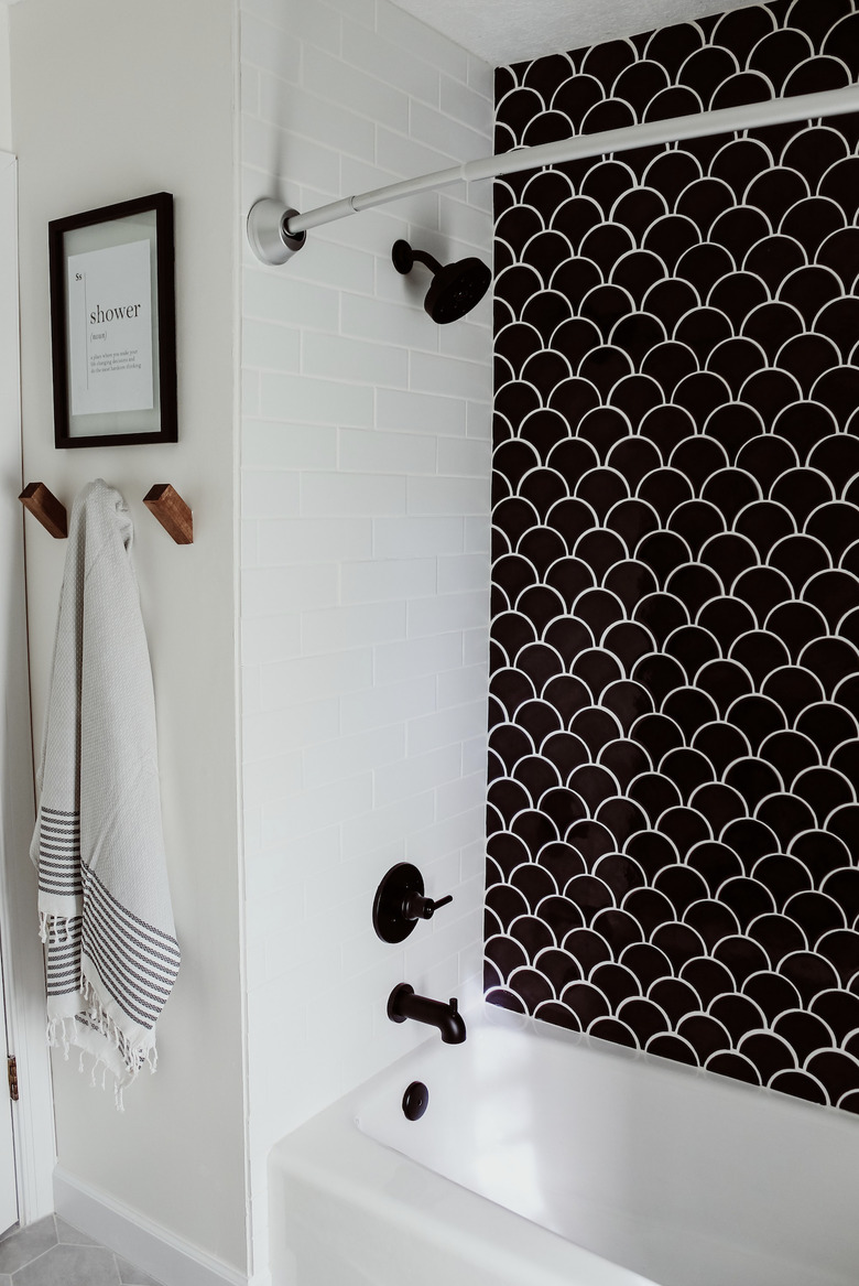 Black plumbing fixtures with black fish scale tile shower wall