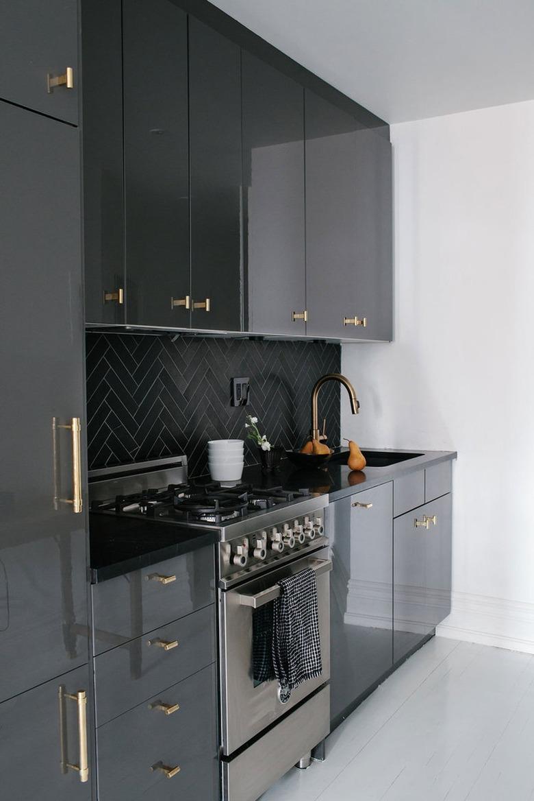 black kitchen with herringbone tile backsplash