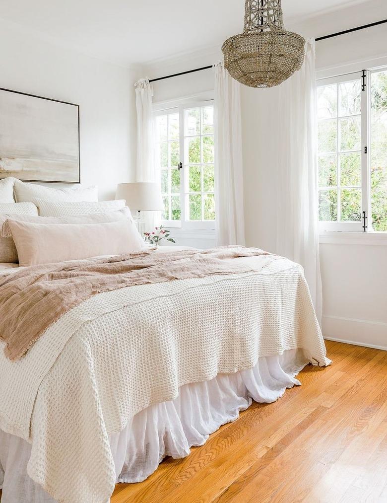 ivory color idea in master bedroom with crystal chandelier and pastel linens