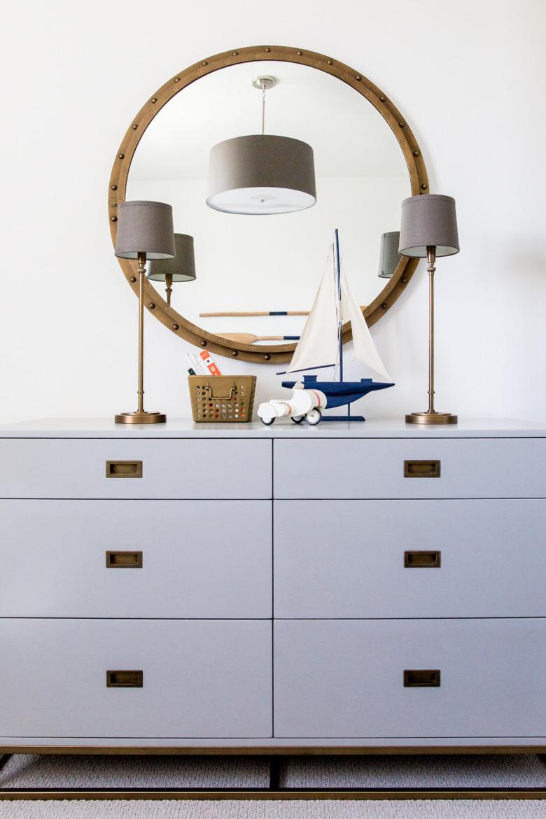 Kids' room organization with gray dresser and round mirror