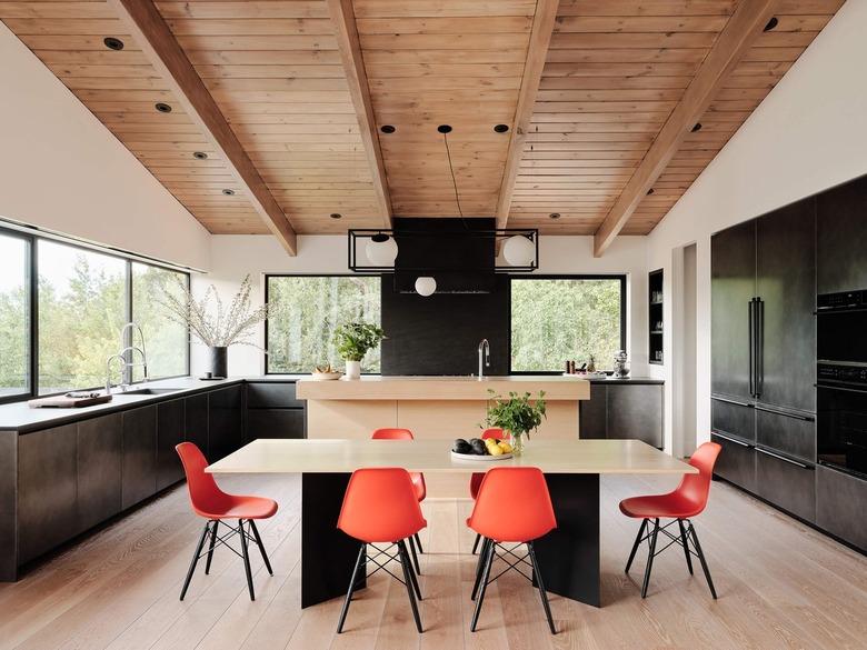 blackened steel kitchen with wood ceiling and orange chairs