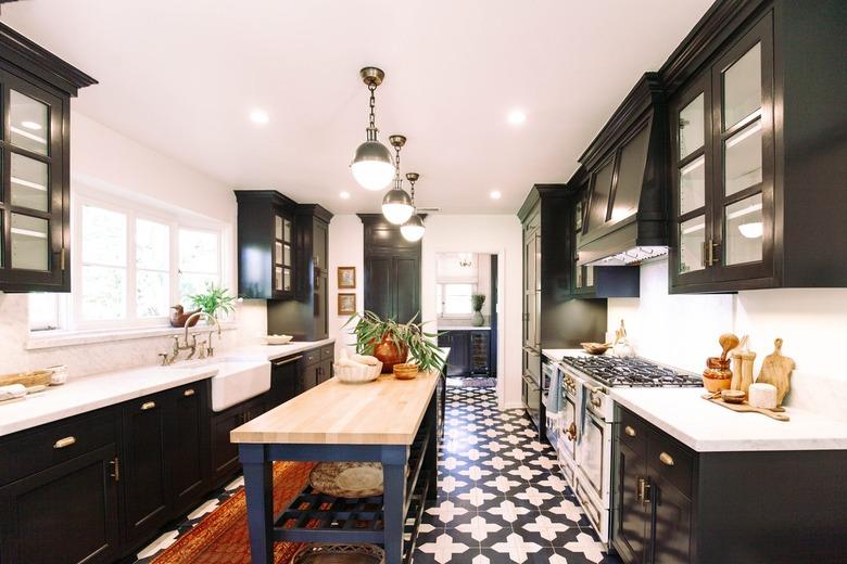 Kitchen with black cabinets, globe pendant lights, ornate tile floor and kitchen island with wood tabletop