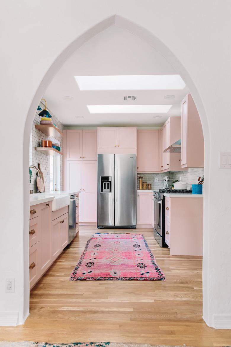 powder pink kitchen with bright pink rug and silver fittings