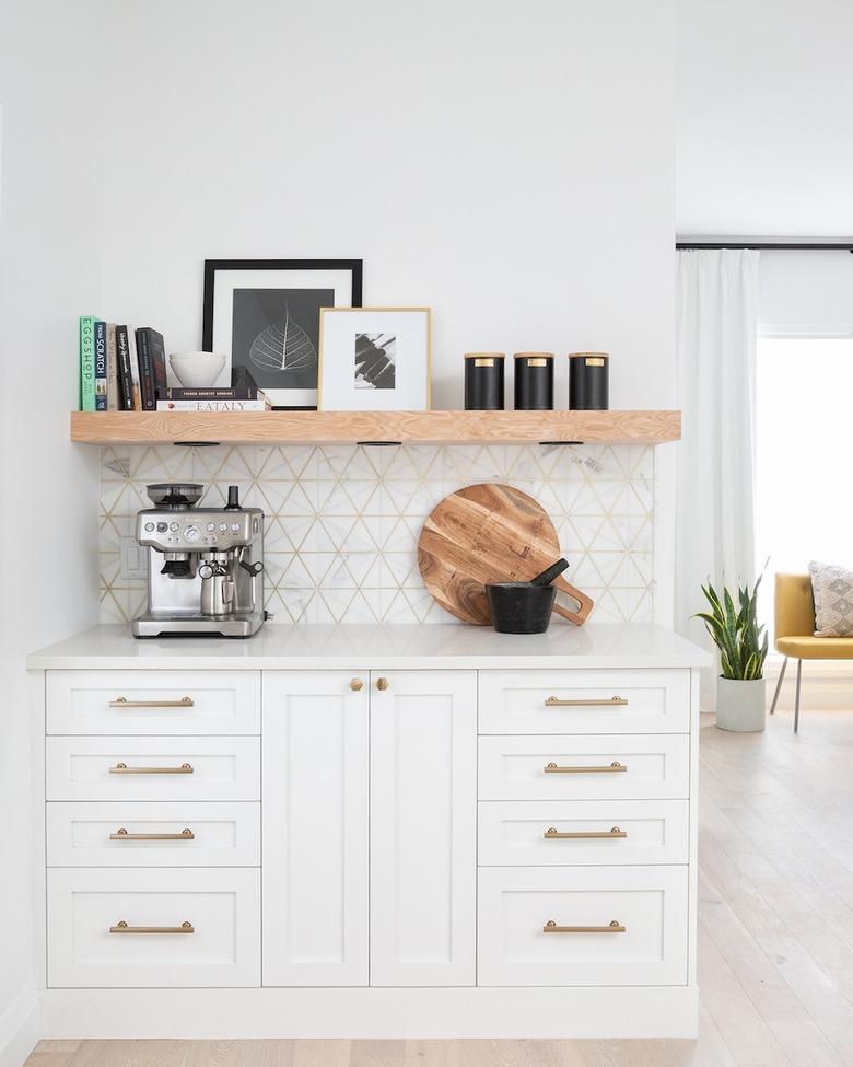 geometric marble and brass backsplash with white cabinets