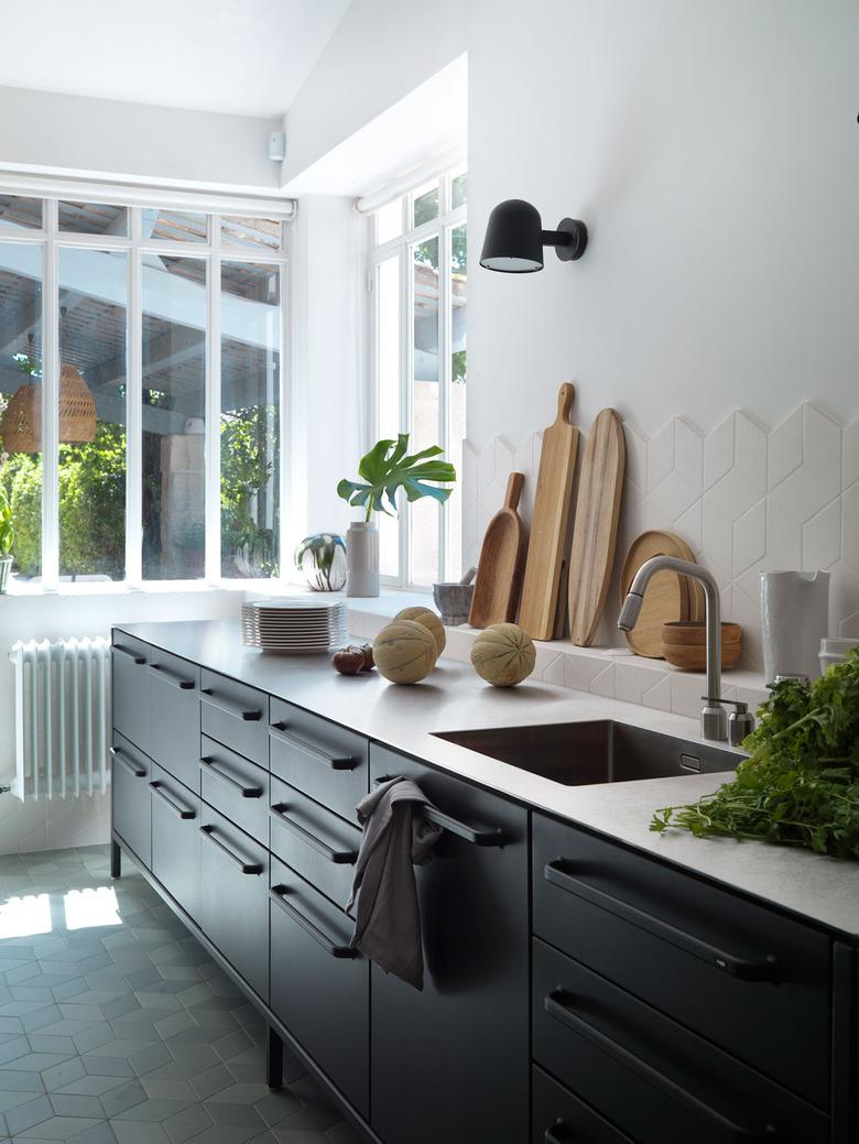 stainless steel kitchen countertops with black cabinets and white tile backsplash