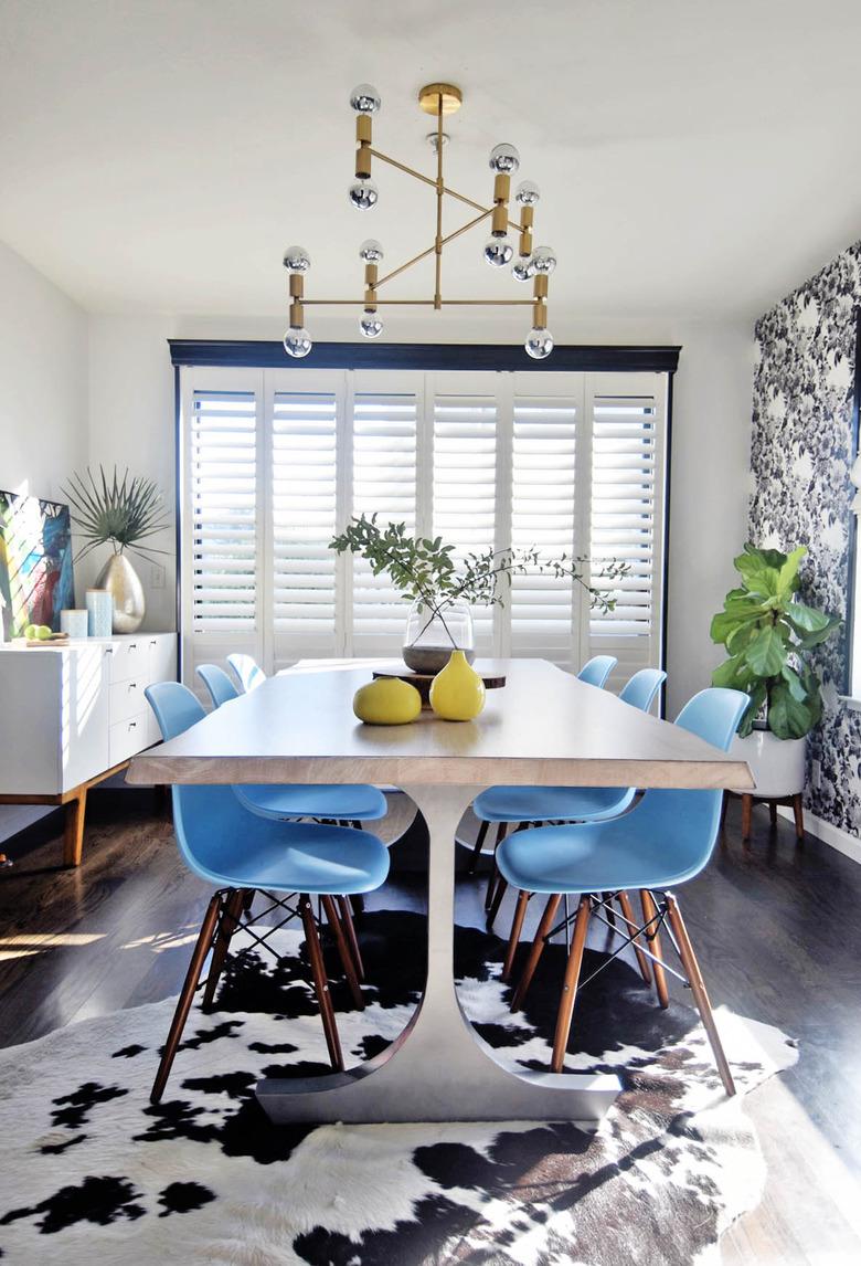 Midcentury dining room idea with blue chairs and patterned wallpaper