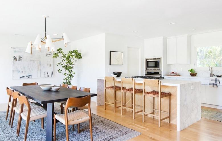 midcentury kitchen island idea with marble waterfall countertop and wood back panel