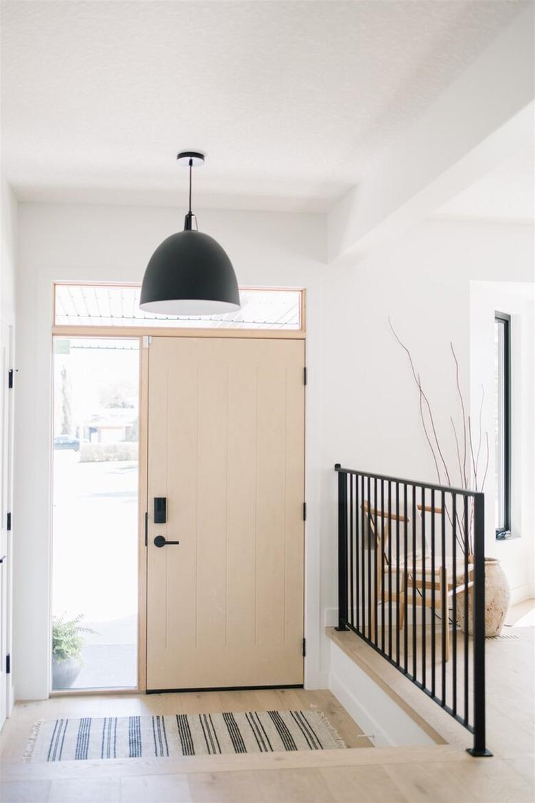 minimalist entryway with large black pendant light and black railing