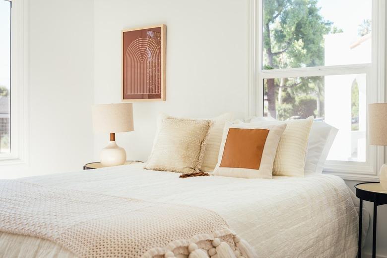 Bedroom with neutral bedding, retro lamps on each side and contemporary wall art