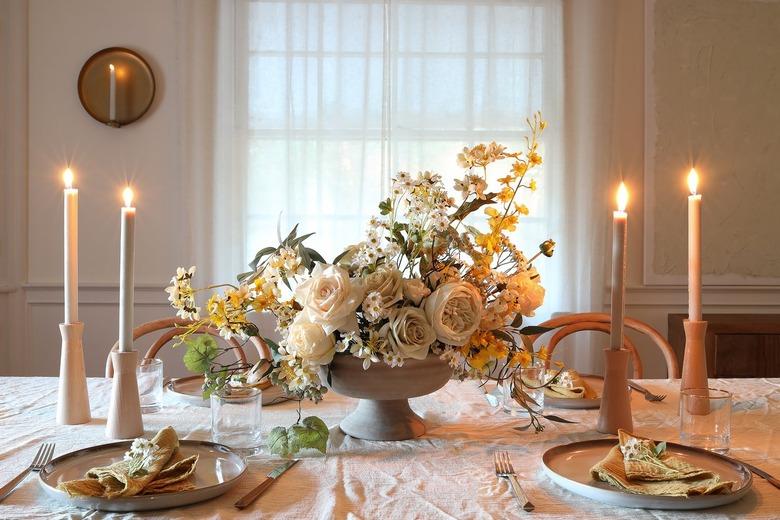 DIY white and yellow spring floral centerpiece on table with candles