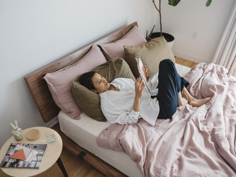 person on bed with multi-colored sheets and side table nearby