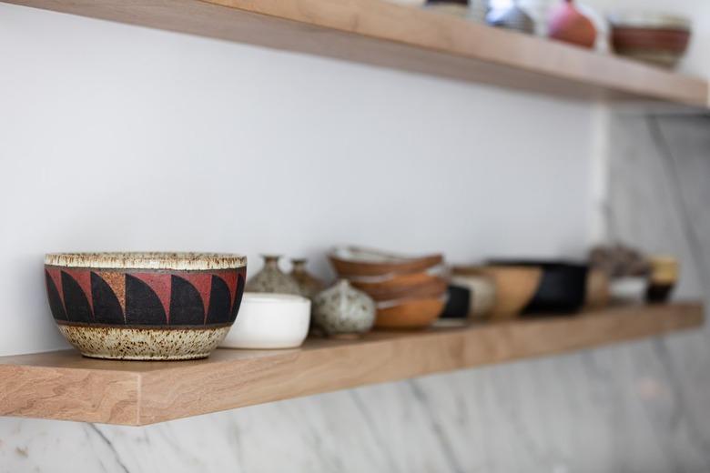 Wood shelves with pottery bowls mounted on a white wall