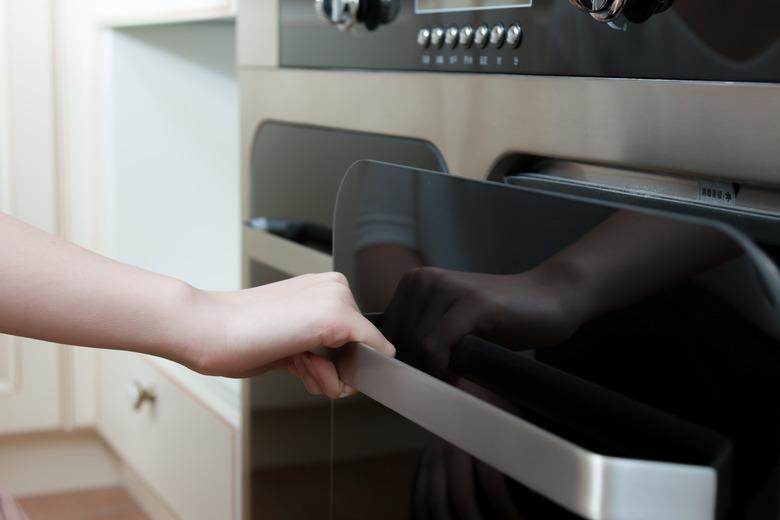 hand open door of oven in modern kitchen