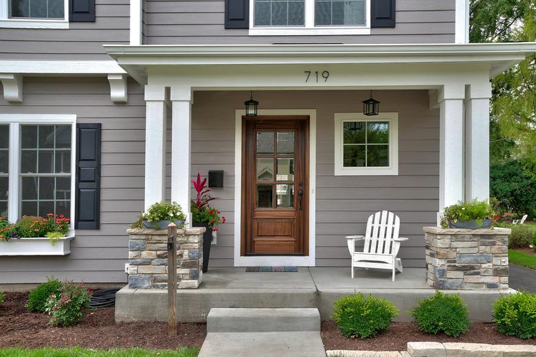 Attractive gray and white house with black shutters; house number and mailbox on front porch.