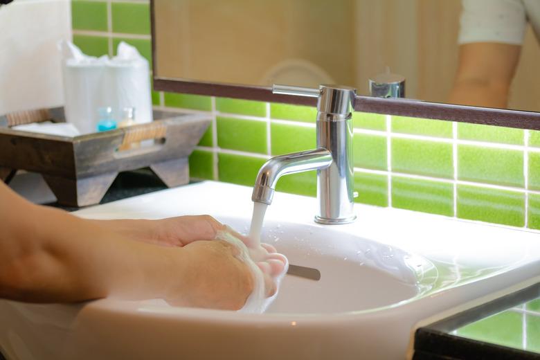 Close-Up Of Woman Washing Hands In Bathroom At Home