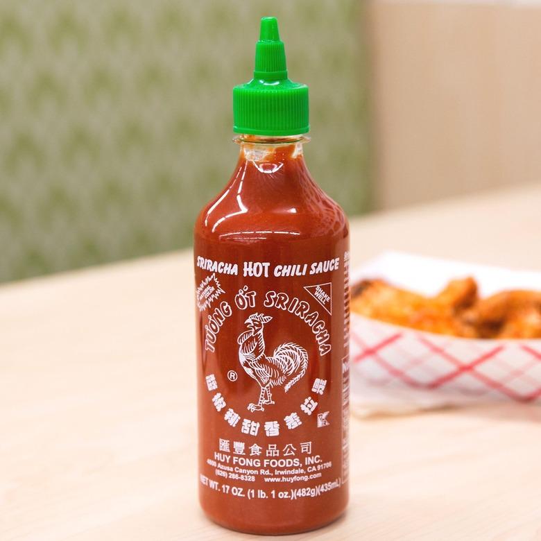 huy fong sriracha chili sauce on wood table with fries