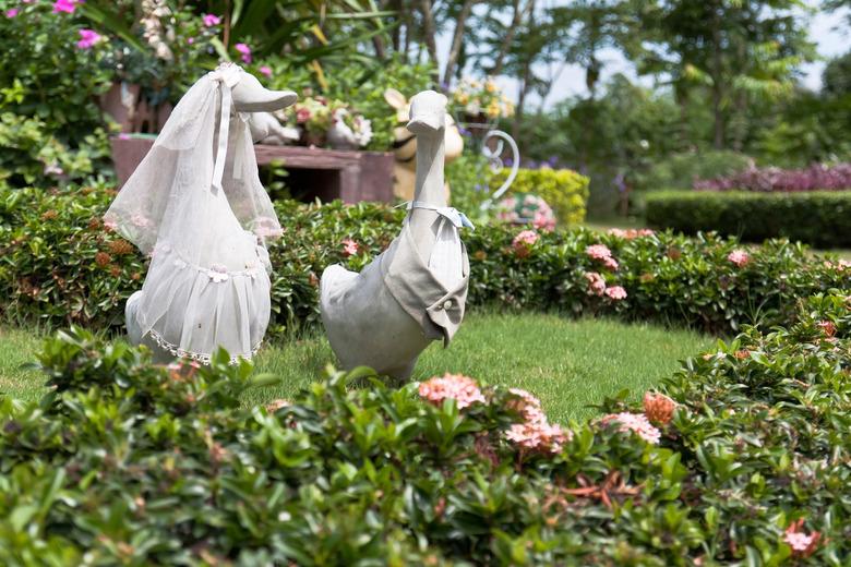 Plaster duck statues dressed for a garden wedding.