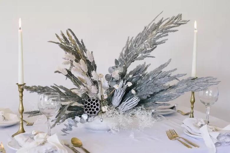 Glittery dried flowers and grass painted gray on table with candles and dishware