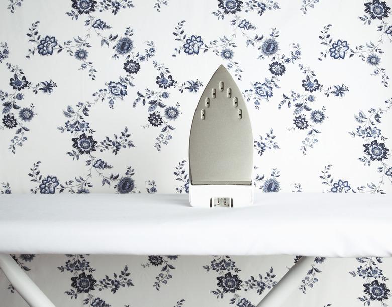 Iron on ironing board with wallpaper pattern in background