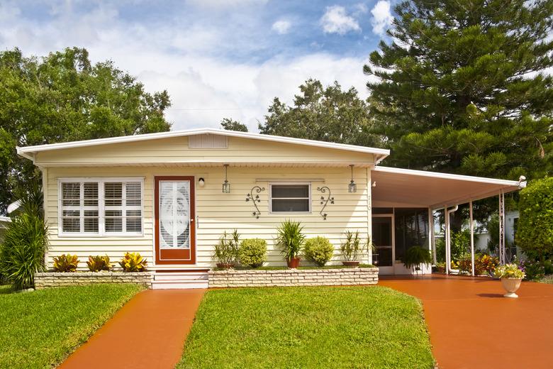 A mobile home with car port and grassy garden