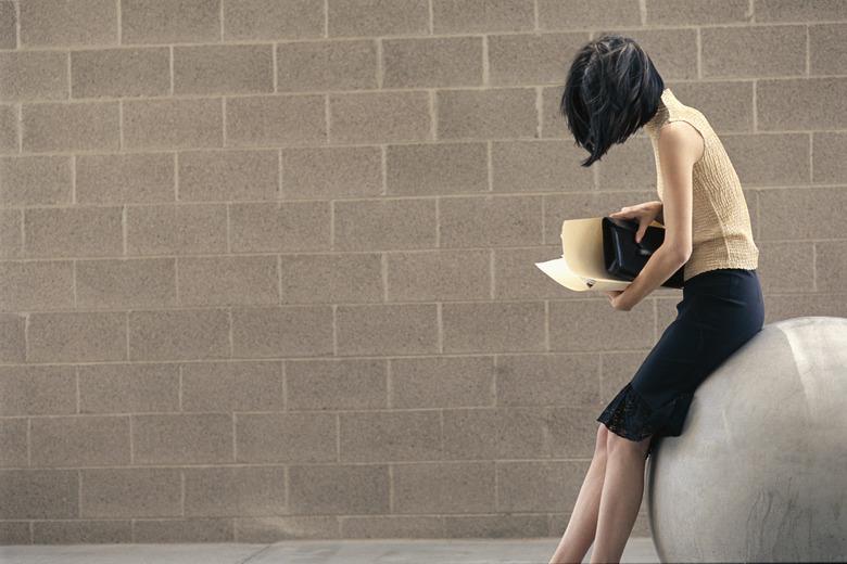 Woman sitting on sculpture of ball