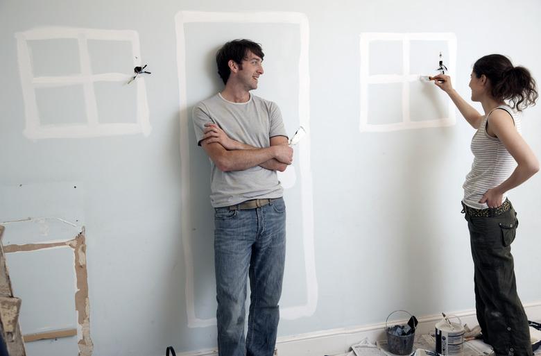 Couple painting doors and windows on an old wall