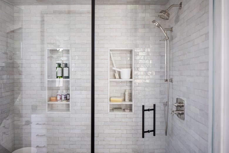 shower with light grey subway tile walls and glass door