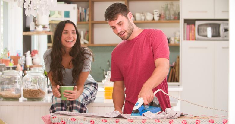 Woman Watching Man Ironing Shirt In Kitchen