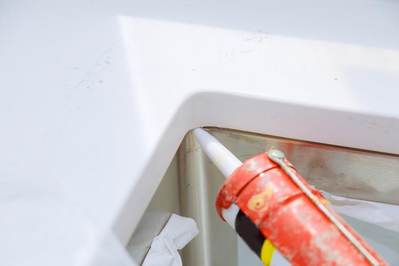 Worker installing granite sink in kitchen silicone sealant