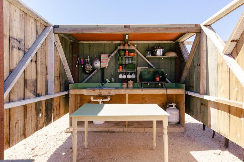 rustic outdoor kitchen with orange corrugated ceiling and green backsplash and countertop