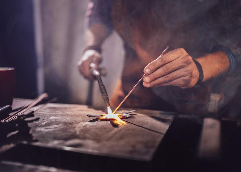 Professional mechanic soldering metal in workshop garage