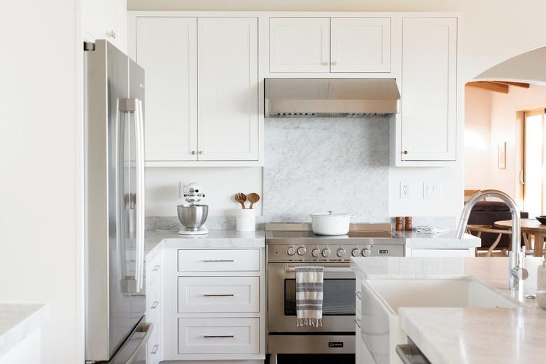 contemporary white kitchen with small area of marble backsplash above the oven