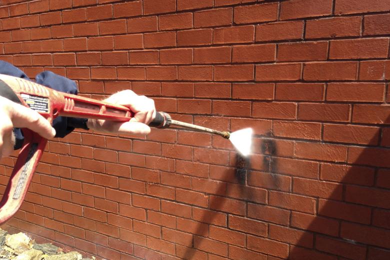 Pressure washing brick wall.