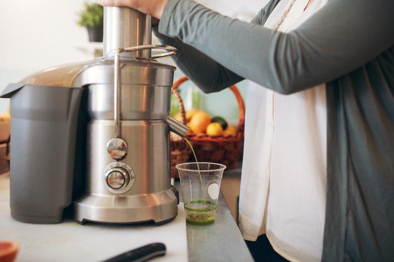 Woman making fruit juice using juicer