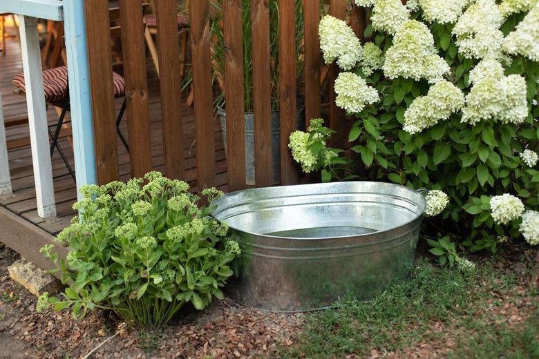 Galvanized tub in garden against wooden wall.