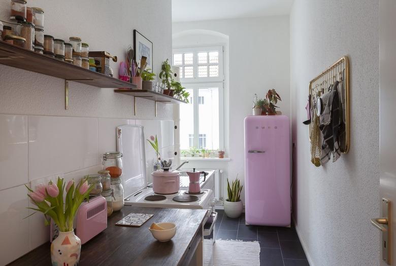 small, narrow kitchen with pink smeg fridge