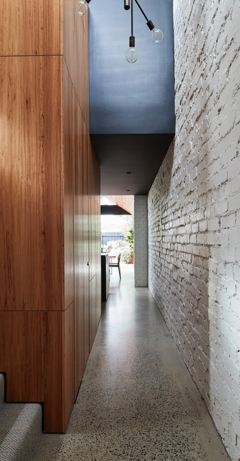 Modern Hallway with wood paneling, brick wall, terrazzo floors.