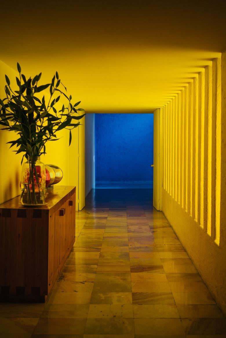 Yellow Modern Hallway leading to a blue room and wood sideboard with plant