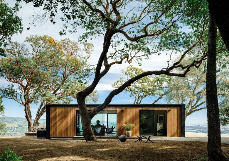 Modern prefab home with flat roof alongside trees