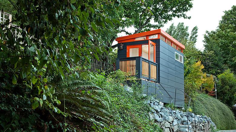 Modern shed painted orange and teal on hillside