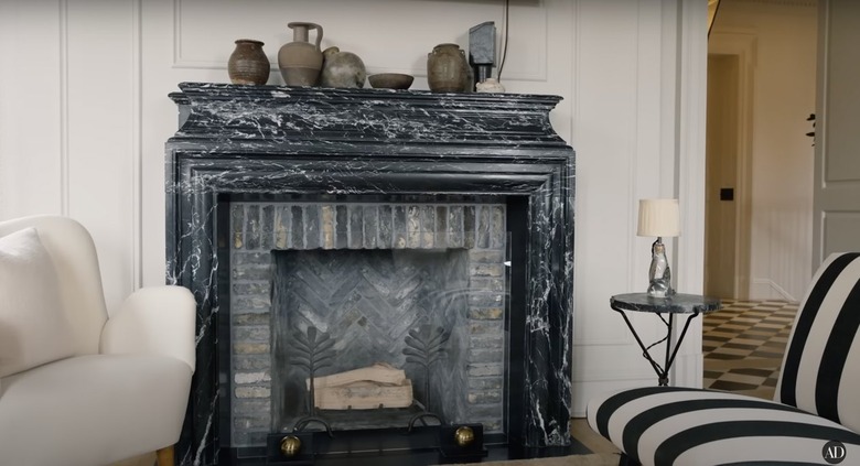 Nate Berkus and Jeremiah Brent's living room with a dark mottled stone mantelpiece above a brick fireplace.