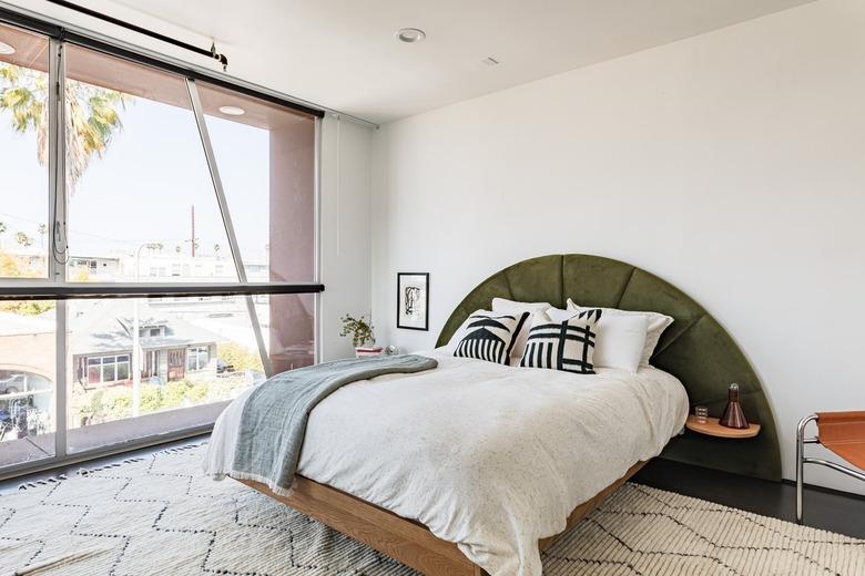 bright room with white walls and olive green headboard