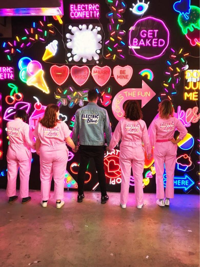 Electric Confetti team in front on neon art–filled wall