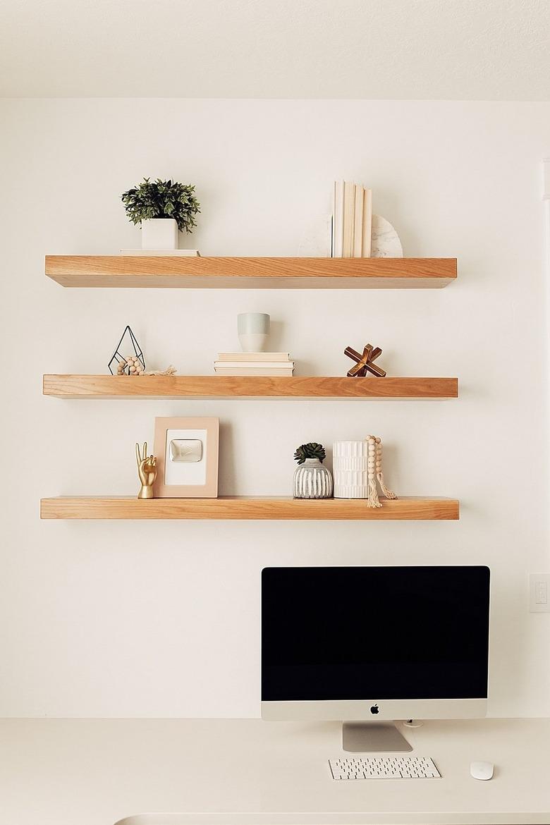 neutral home office with desktop computer and floating shelves