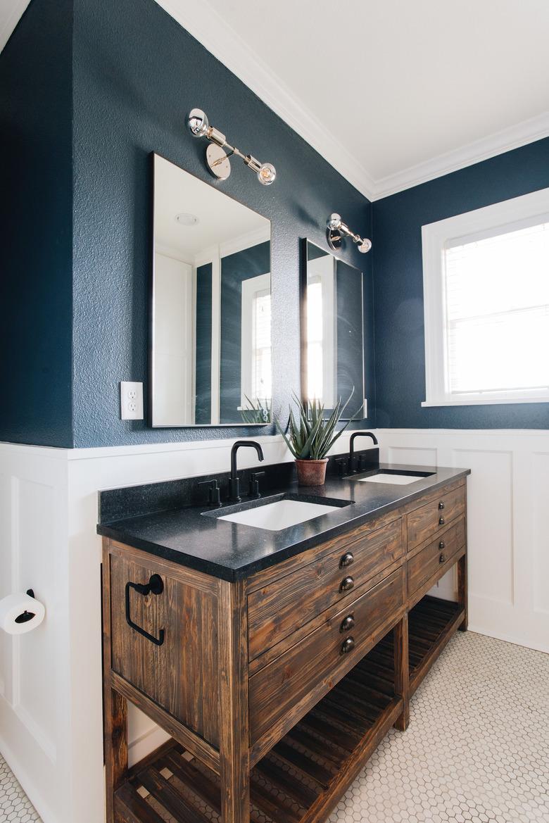 bathroom space with white and blue walls with wood bathroom vanity with black countertop