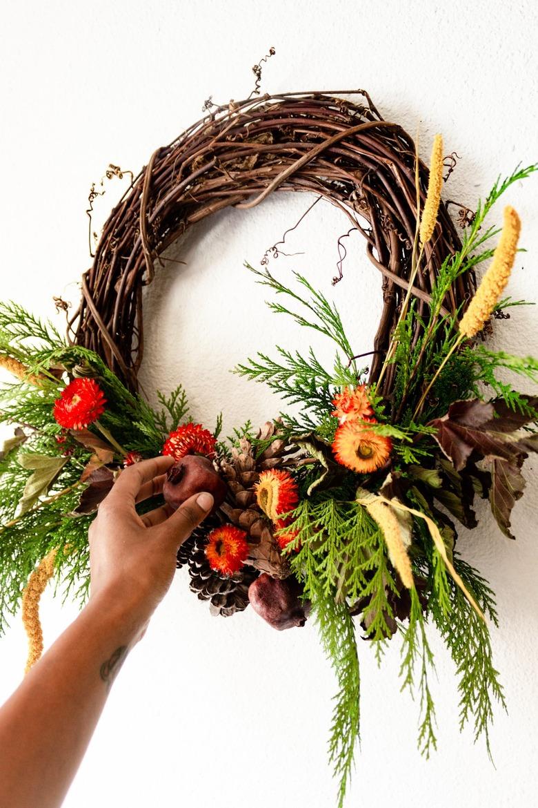 attaching dried pomegranates to a grapevine wreath base