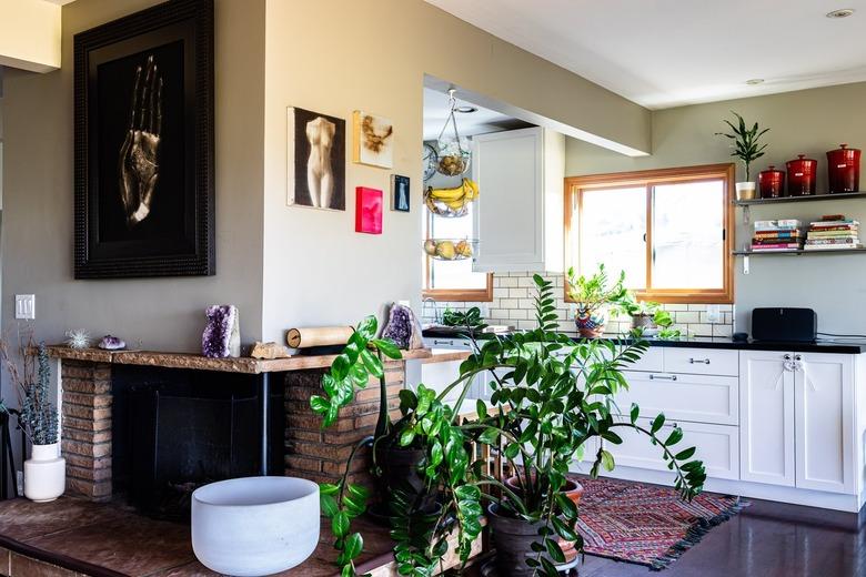 A living room with a brick fireplace plants and dark wood floors