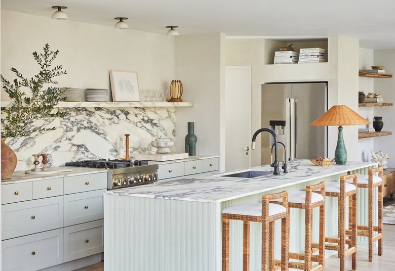 Open concept kitchen with mint green island, marble backsplash and cream plaster walls.